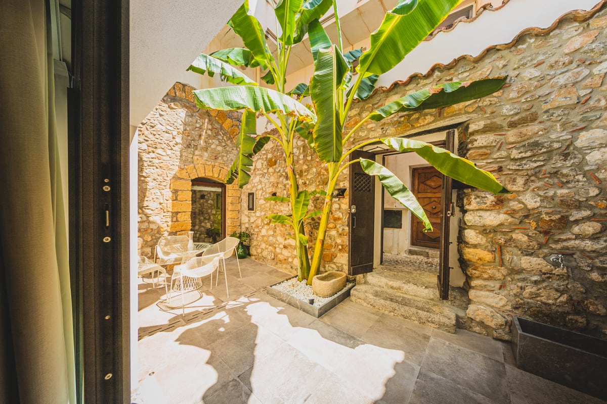Il cortile alla luce del giorno, con tavolo, sedute e foglie di banano.