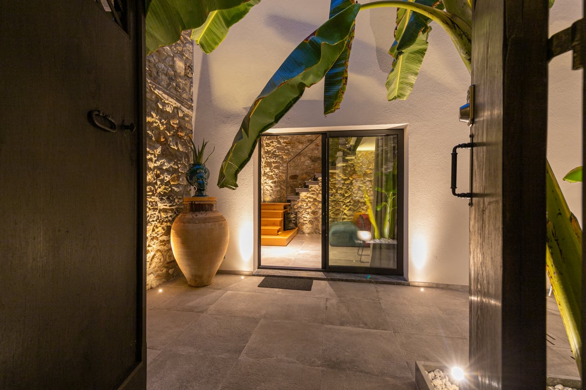 Dalla soglia, il cortile e la vetrata sulla scala, incorniciati dalle ante scure.