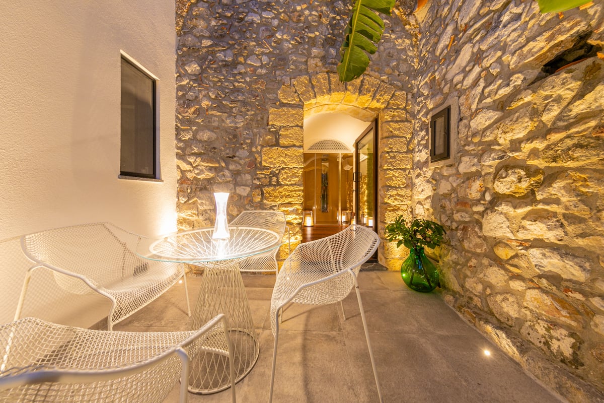 Il tavolo e le sedute trasparenti nel cortile illuminato la sera.